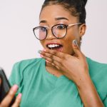 Persoană care citește informații și recenzii pe telefon înainte de cumpărare